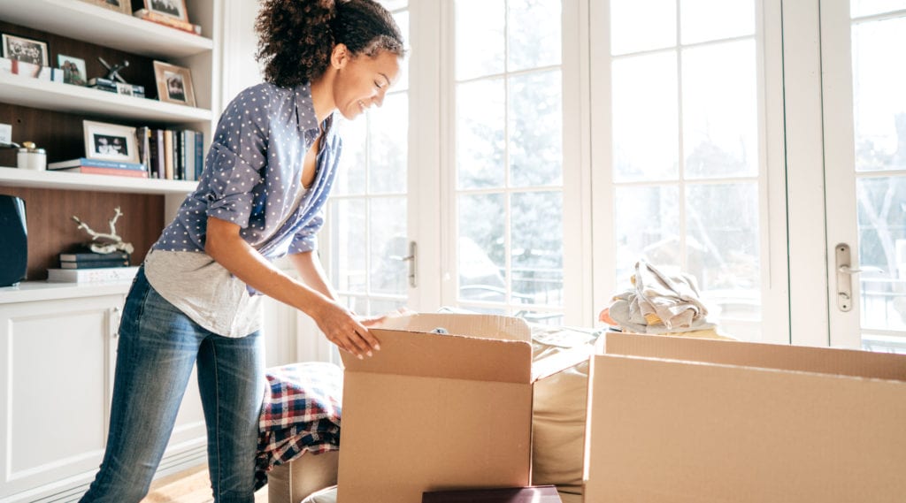 A young woman packs her belongings into the free moving boxes she found.