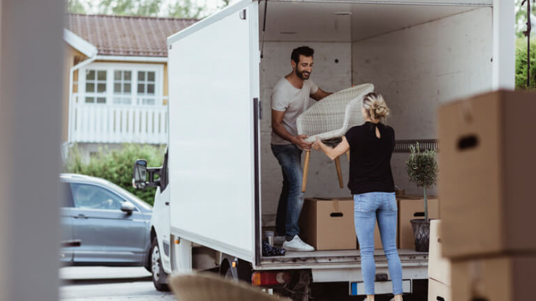 Smiling male and female partners unloading chair from van